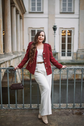 a lady in a white slim sweater, a red jacket and a pair of white pants